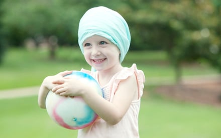 A child with cancer holding ball.