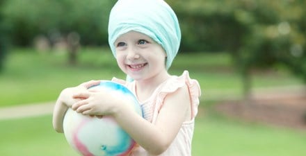 A child with cancer holding ball.