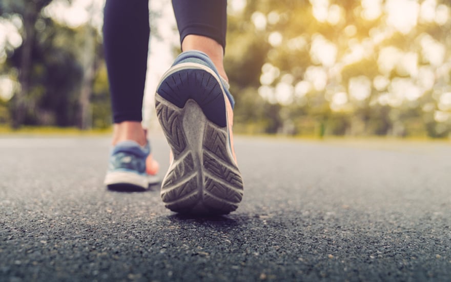 A close-up of a person's sneakers walking on pavement.