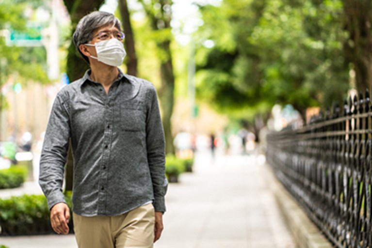 Masked man walking down the street.
