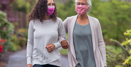 Two women wearing masks walking outdoors for physical activity.