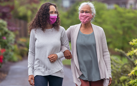 Two women wearing masks walking outdoors for physical activity.