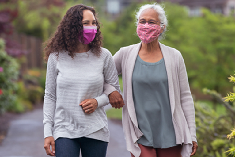 Two women wearing masks walking outdoors for physical activity.