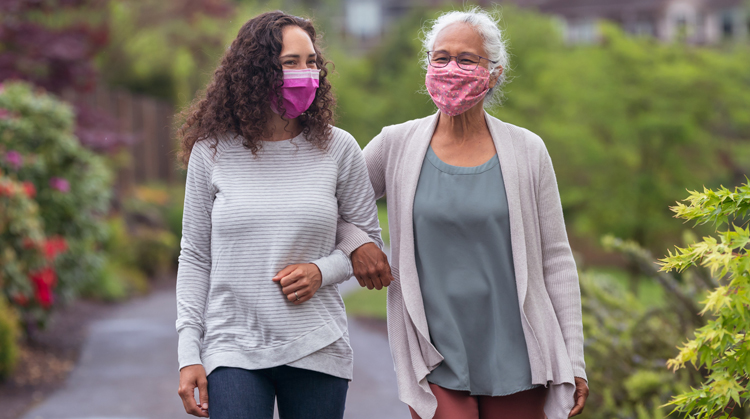 Two women wearing masks walking outdoors for physical activity.