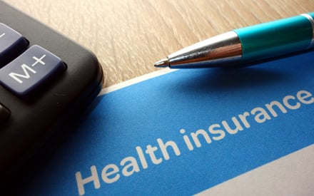 A calculator, pen, and a health insurance document on a table.