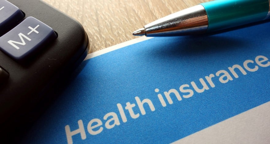 A calculator, pen, and a health insurance document on a table.