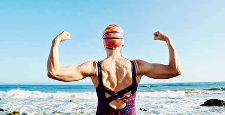 Swimmer flexing arm muscles in front of ocean