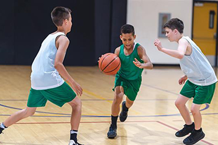 Young boys playing basketball in a gym.