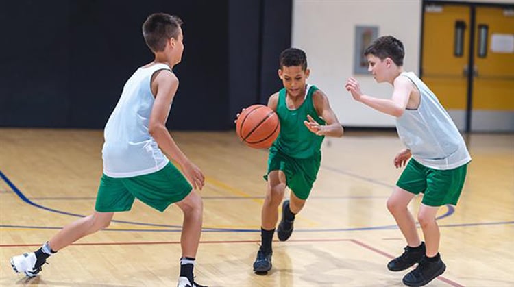 Young boys playing basketball in a gym.