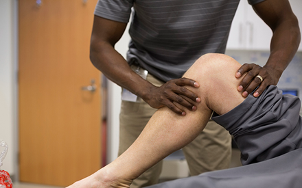 A physical therapist uses hands on therapy on a person's knee.