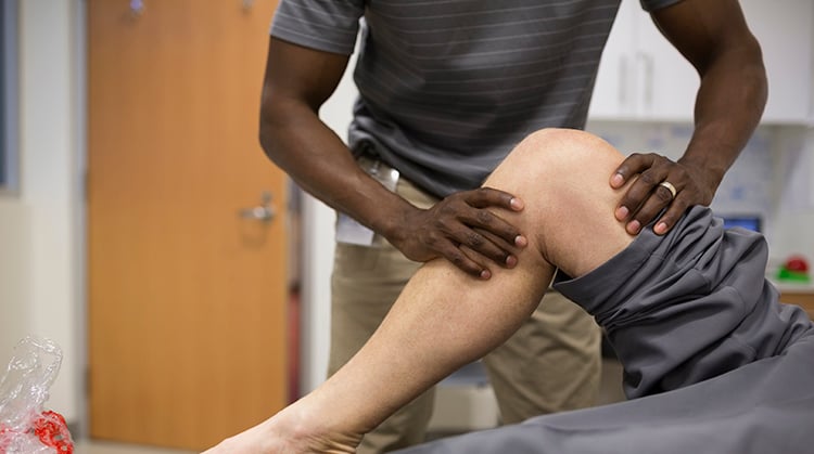 A physical therapist uses hands on therapy on a person's knee.