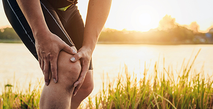 Man holding kneecap in pain.