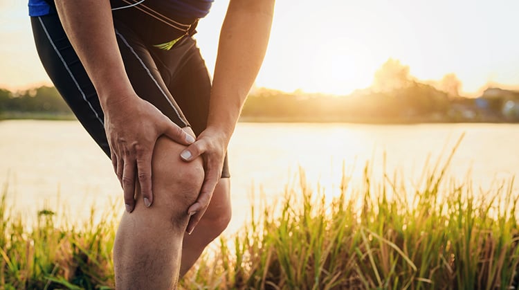 Man holding kneecap in pain.