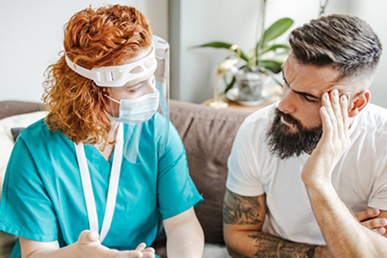 Patient and PT wearing masks discussing an issue.