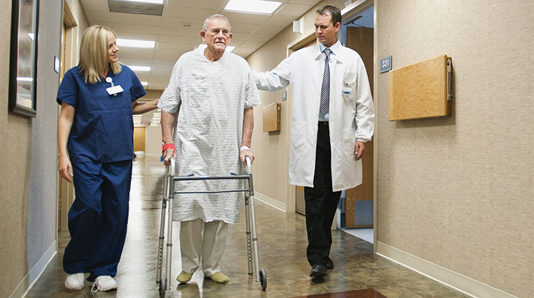 Male patient walking with a physical therapist and doctor in a hospital