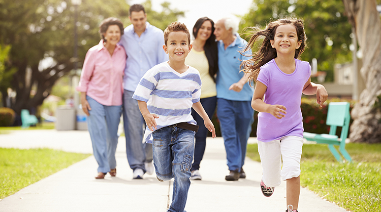 Multi-generational family walking down neighborhood sidewalk