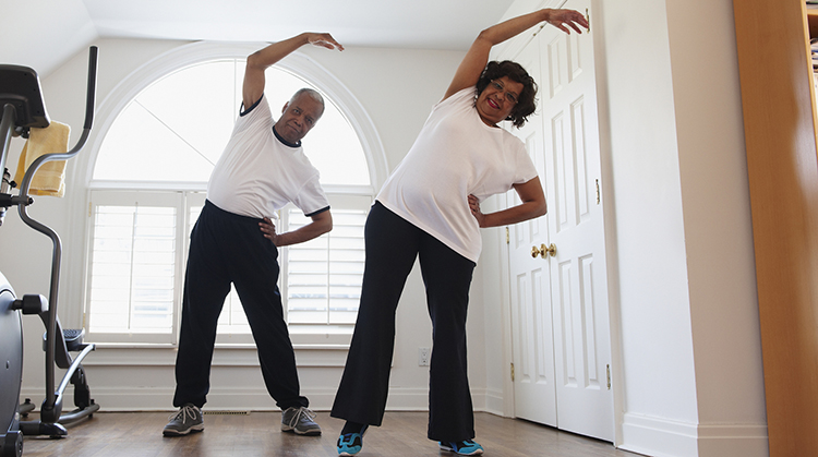 Older adult couple doing side bend exercises.