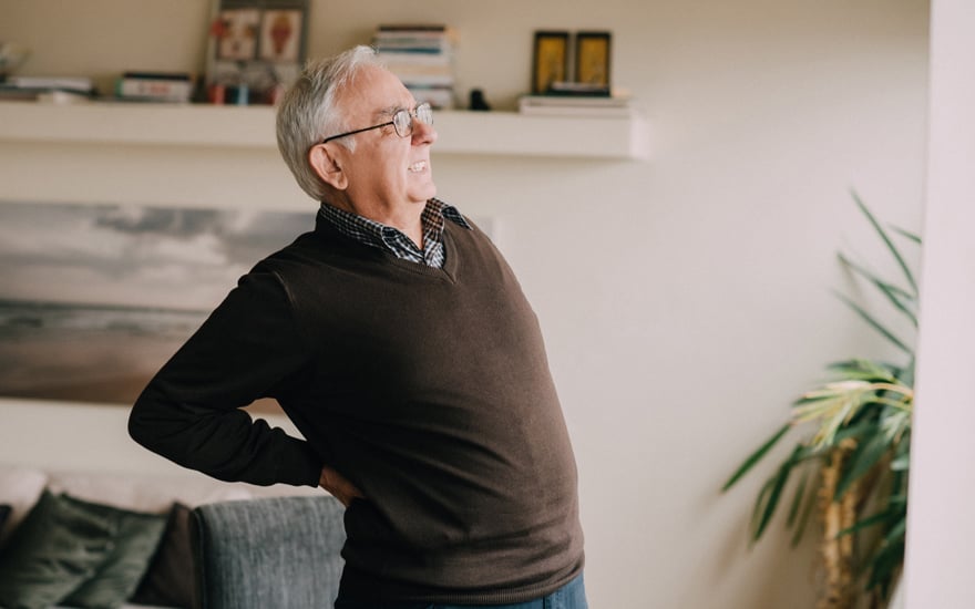 An older adult male bending backwards with low back pain.