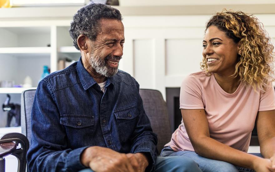 An older adult black man sitting with his daughter.