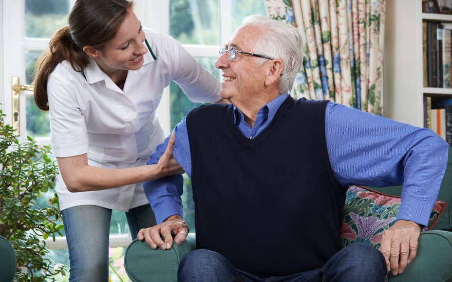 An older adult being helped to stand by a PT.