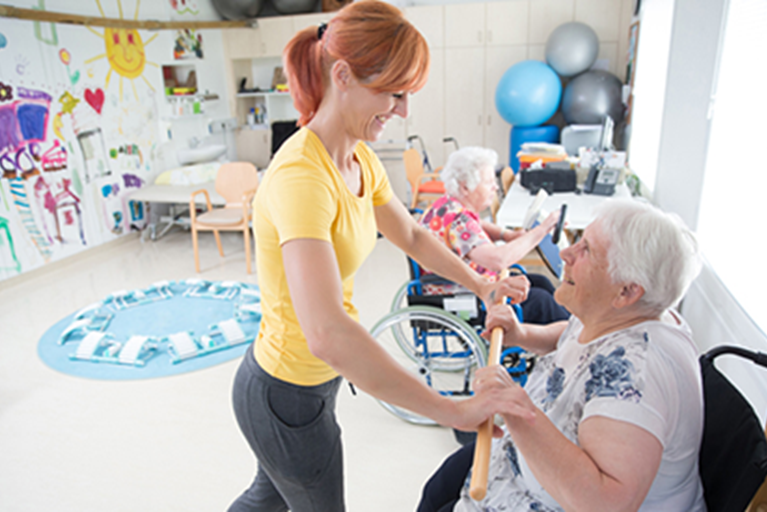 Older adult being helped by a PT during rehab.