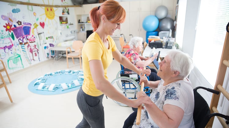 Older adult being helped by a PT during rehab.