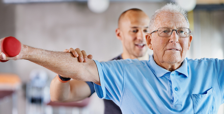 Physical Therapist assisting older adult with strength exercises for shoulders.