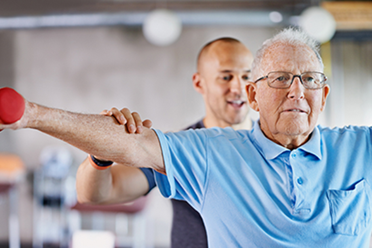 Physical Therapist assisting older adult with strength exercises for shoulders.