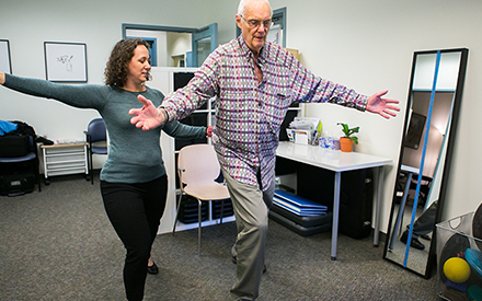 A physical therapist is working with a patient on large movement activities.