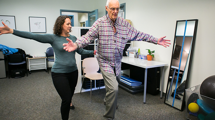 A physical therapist is working with a patient on large movement activities.