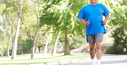 Man in blue shirt walking outdoors.