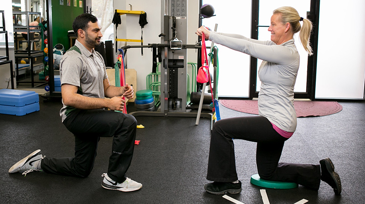 Woman working with physical therapist using bands