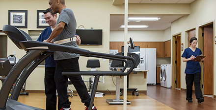 Older adult workng with a PT on treadmill.