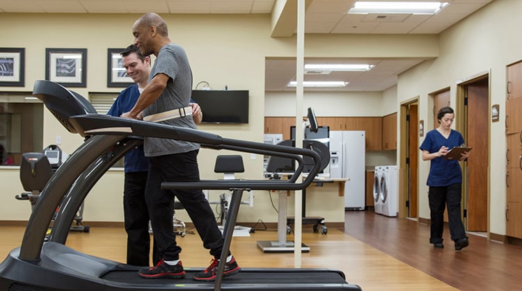 Older adult workng with a PT on treadmill.