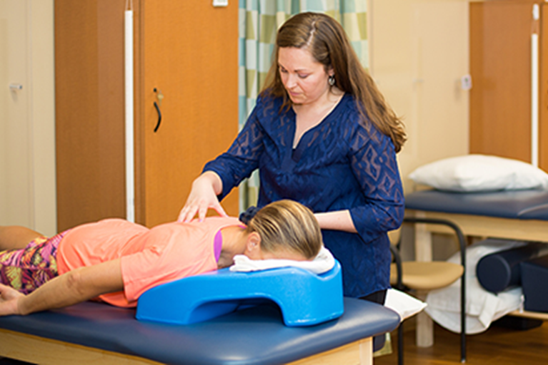 A physical therapist performing hands-on therapy on a patient to treat back pain. 