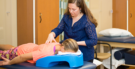 A physical therapist performing hands-on therapy on a patient to treat back pain. 