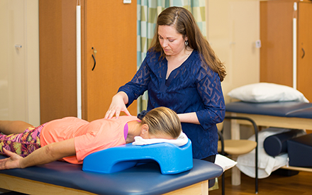 A physical therapist performing hands-on therapy on a patient to treat back pain. 