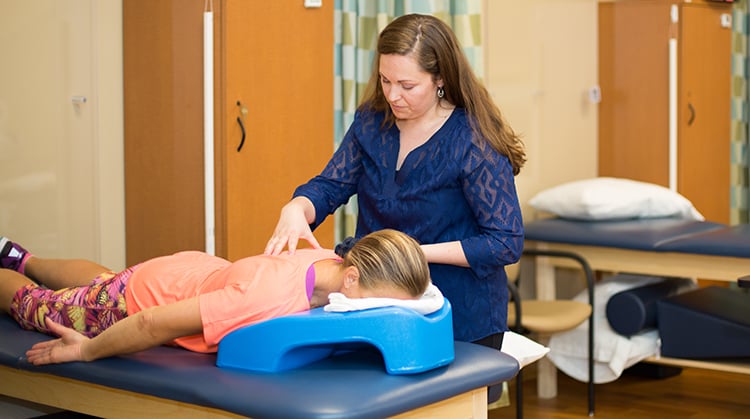 A physical therapist performing hands-on therapy on a patient to treat back pain. 