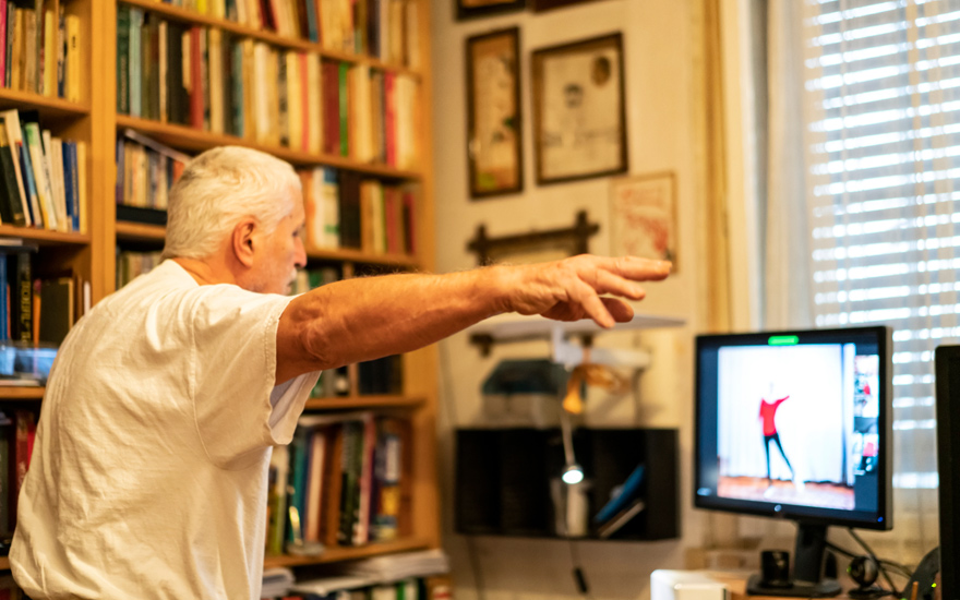 An older adult does physical therapy exercises via telehealth.