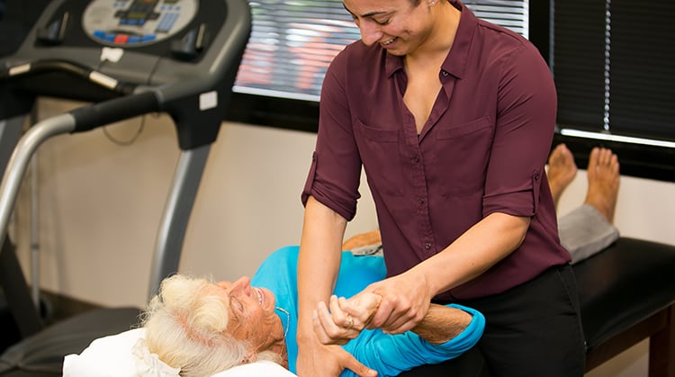 A physical therapist using manual therapy to mobilize an older adult's shoulder.
