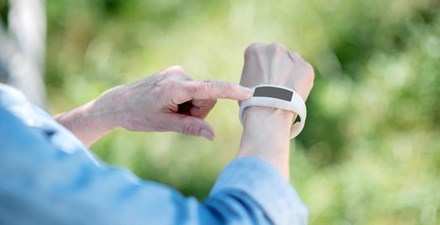 An older adult using a wearable to track steps for physical activity.