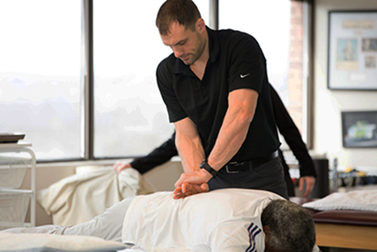 A physical therapist providing treatment on a person's low back.
