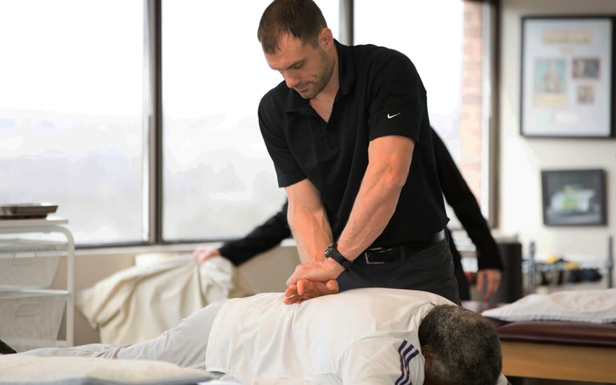 A physical therapist providing treatment on a person's low back.