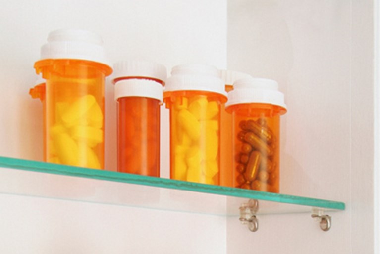 Several bottles of unused pills in a medicine cabinet.