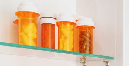 Several bottles of unused pills in a medicine cabinet.