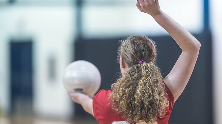 A vollyball player preparing to make an overhead serve.