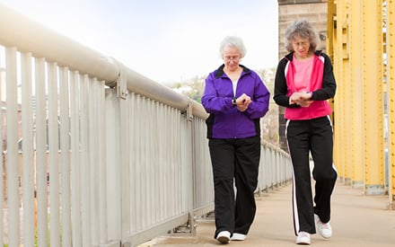 Two women with grey hair and glasses walking.