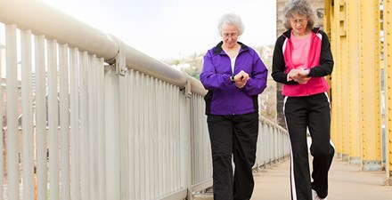 Two women with grey hair and glasses walking.