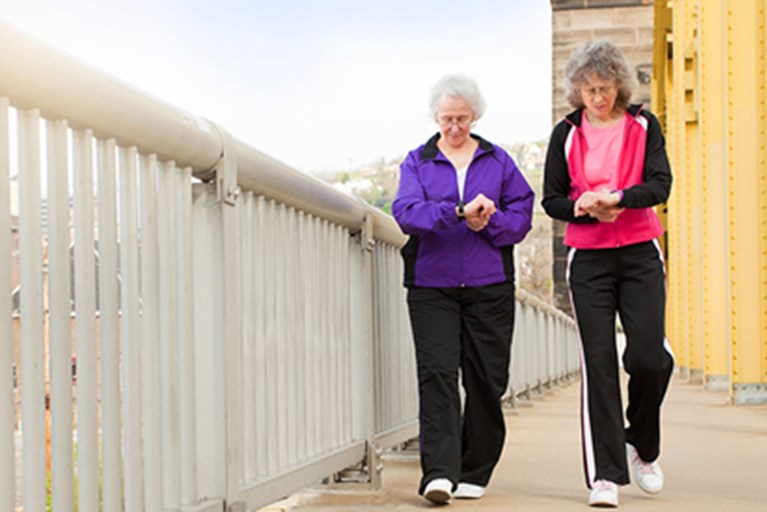 Two women with grey hair and glasses walking.