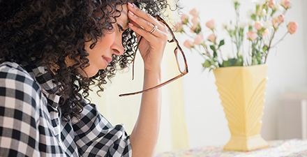 Woman with fingers on forehead, in pain from a headache